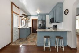 kitchen with a peninsula, blue cabinetry, light countertops, and stainless steel fridge with ice dispenser