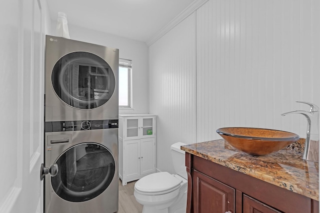 bathroom featuring stacked washer and dryer, vanity, and toilet