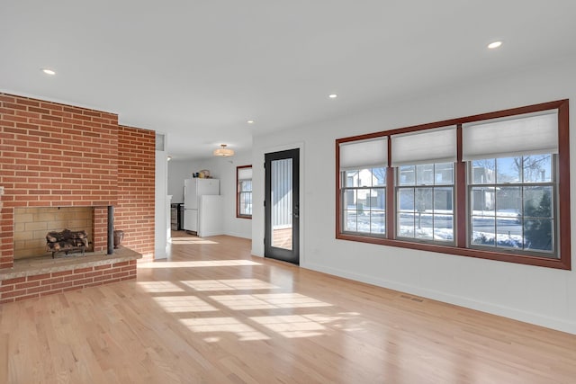 unfurnished living room featuring a fireplace and light hardwood / wood-style floors