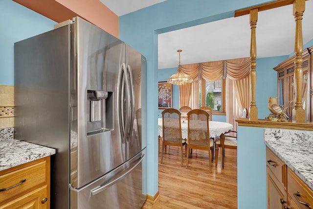 kitchen featuring tasteful backsplash, stainless steel refrigerator with ice dispenser, light stone counters, and light hardwood / wood-style floors