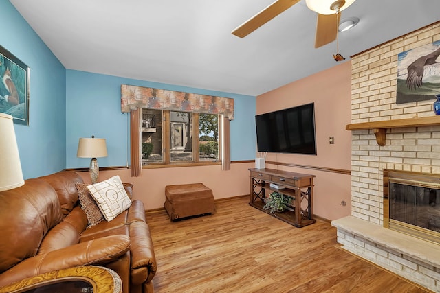 living room with a fireplace, ceiling fan, and light wood-type flooring