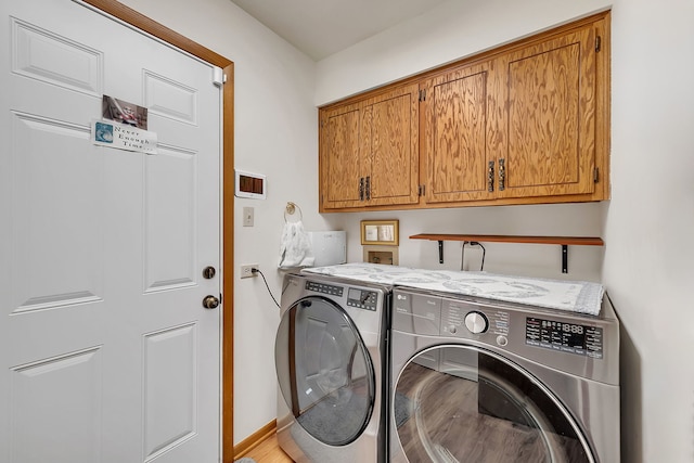 clothes washing area featuring cabinets and washer and clothes dryer