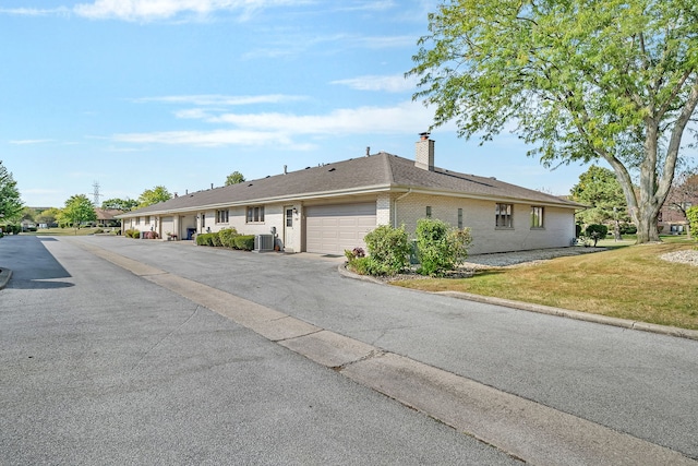 view of front facade featuring a garage, a front lawn, and central air condition unit