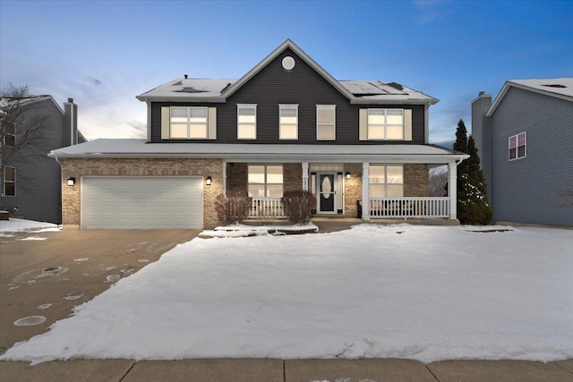 view of property featuring a porch, a garage, and solar panels