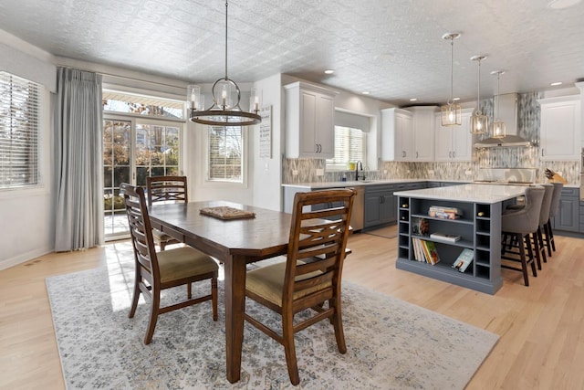 dining area featuring light wood-style floors, baseboards, a textured ceiling, and recessed lighting