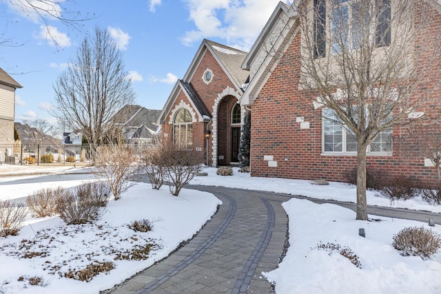 tudor house featuring brick siding and fence