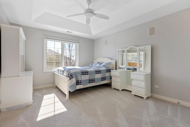 bedroom featuring light colored carpet, a tray ceiling, visible vents, and baseboards