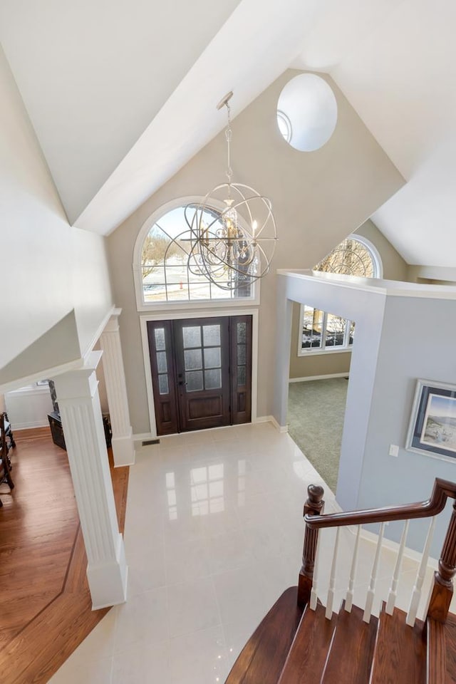 tiled foyer with high vaulted ceiling, stairs, baseboards, and an inviting chandelier