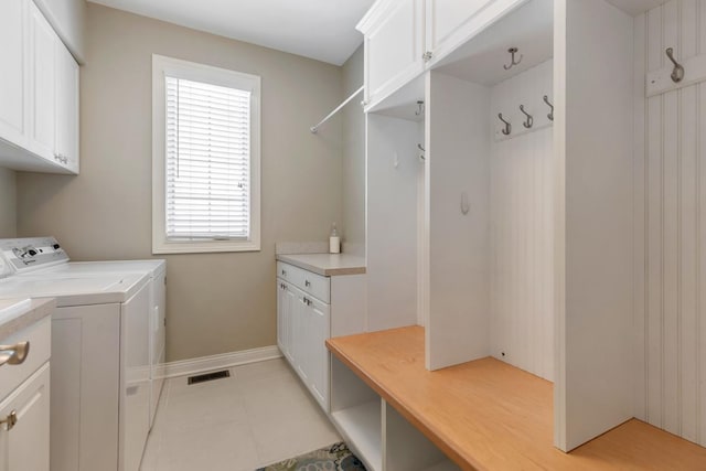 clothes washing area with cabinet space, light tile patterned floors, baseboards, visible vents, and separate washer and dryer