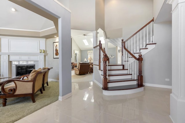 entrance foyer with a glass covered fireplace, light tile patterned floors, baseboards, and stairs