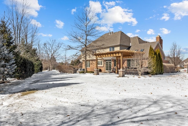 snow covered house with a chimney and a pergola