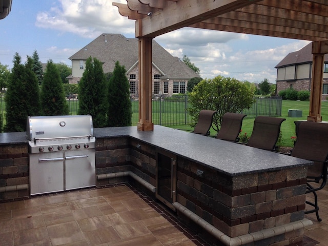 view of patio with a grill, fence, an outdoor kitchen, and a pergola