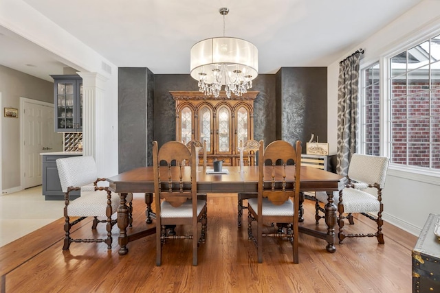 dining room featuring baseboards, light wood-style floors, visible vents, and a notable chandelier