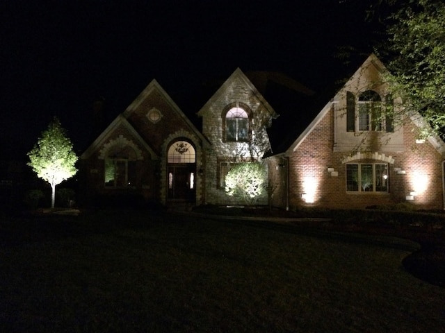 french country home featuring stone siding and brick siding