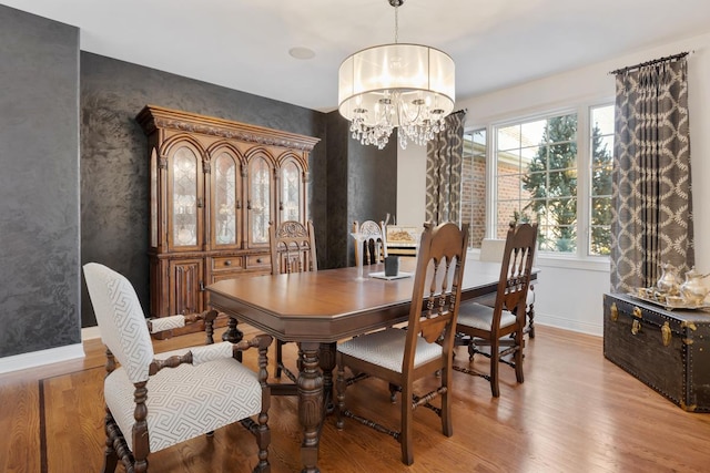 dining space featuring baseboards, light wood finished floors, and a notable chandelier