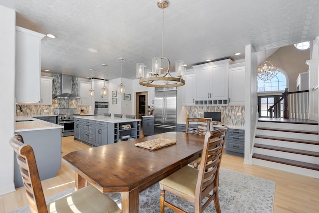 dining room featuring a chandelier, stairway, light wood-type flooring, and recessed lighting