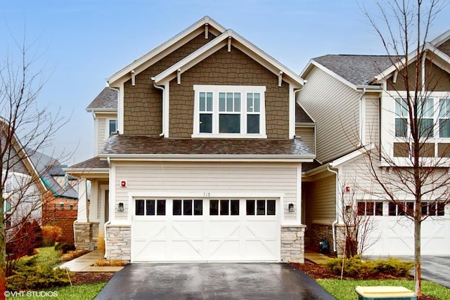 craftsman house featuring a garage, driveway, stone siding, and a shingled roof