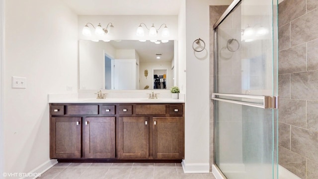 full bath featuring a stall shower, double vanity, a sink, and tile patterned flooring