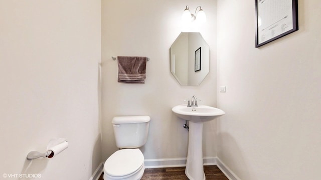bathroom featuring toilet, wood finished floors, a sink, and baseboards