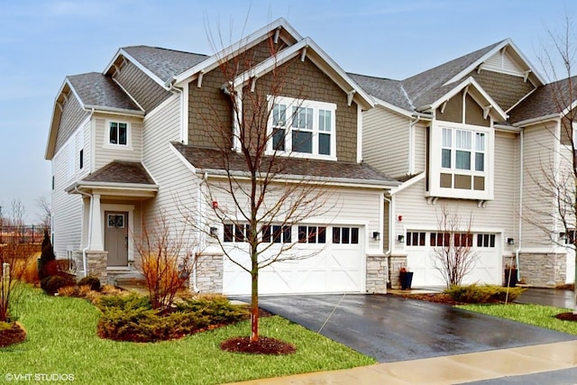 craftsman-style house with driveway, a garage, stone siding, and roof with shingles
