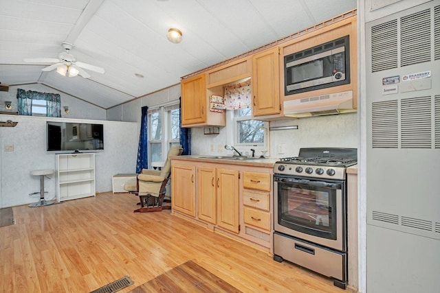 kitchen featuring lofted ceiling, light wood-style flooring, stainless steel appliances, under cabinet range hood, and light brown cabinets