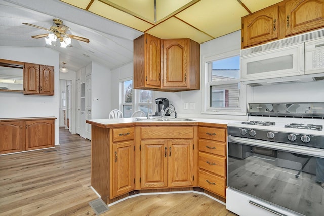 kitchen with lofted ceiling, white appliances, light wood-style flooring, and brown cabinetry