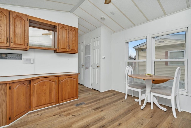 kitchen featuring visible vents, light wood-style floors, vaulted ceiling, light countertops, and brown cabinets