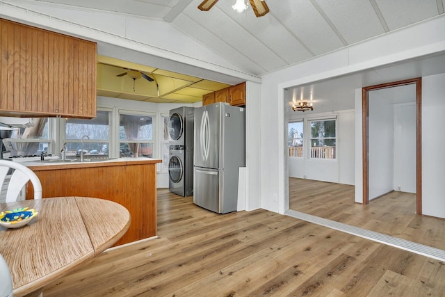 kitchen featuring light wood finished floors, freestanding refrigerator, stacked washer / dryer, ceiling fan, and a sink