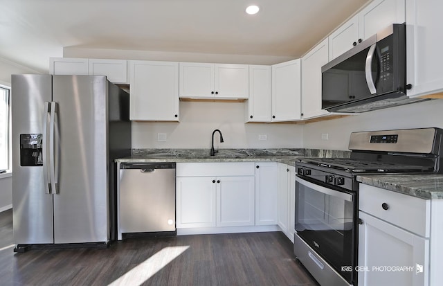 kitchen featuring dark stone countertops, appliances with stainless steel finishes, sink, and white cabinets