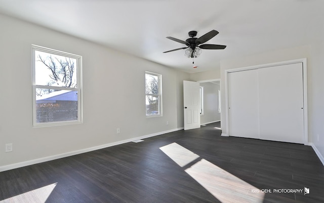 unfurnished bedroom with dark wood-type flooring, ceiling fan, and a closet