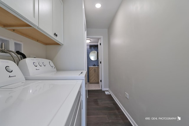 washroom featuring washer and dryer, dark hardwood / wood-style floors, and cabinets