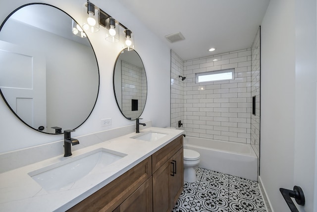 full bathroom with tile patterned flooring, tiled shower / bath, vanity, and toilet