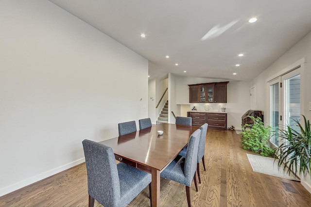 627 68th St, Willowbrook, IL 60527 - dining area featuring wood finished floors, visible vents, baseboards, lofted ceiling, and stairs