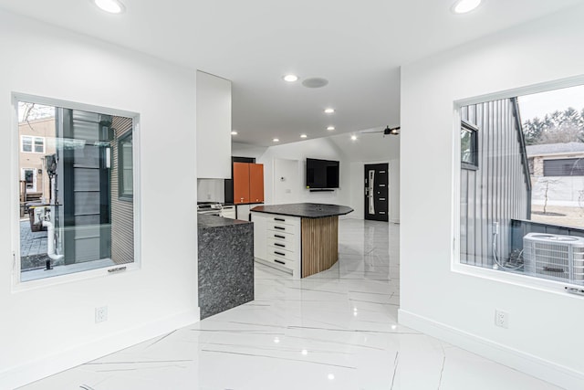 kitchen with white cabinetry, a kitchen island, lofted ceiling, and ceiling fan