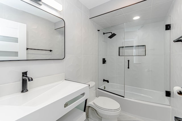 full bathroom featuring vanity, tile walls, shower / bath combination with glass door, and toilet