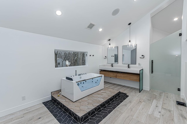 bathroom with hardwood / wood-style flooring, lofted ceiling, vanity, and a tub