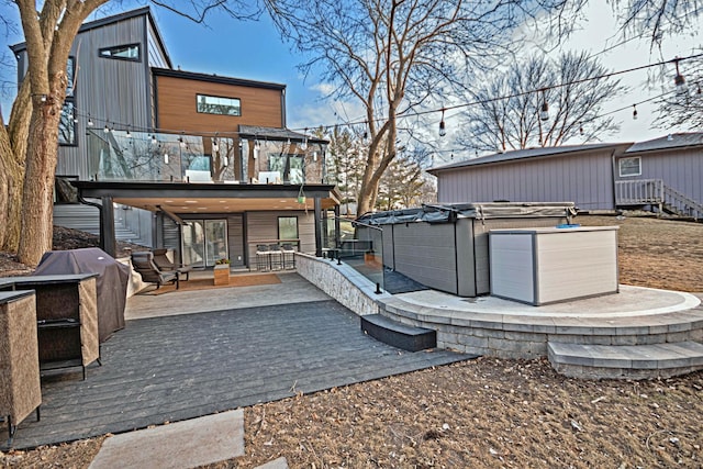 rear view of property featuring a wooden deck and a hot tub