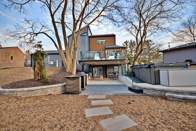 rear view of property with a jacuzzi and a patio