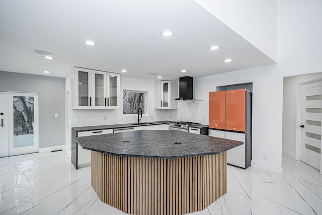 kitchen with white cabinetry, wall chimney range hood, sink, and a kitchen island