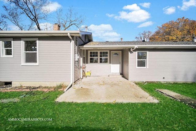 back of property with a yard, a patio, and a chimney