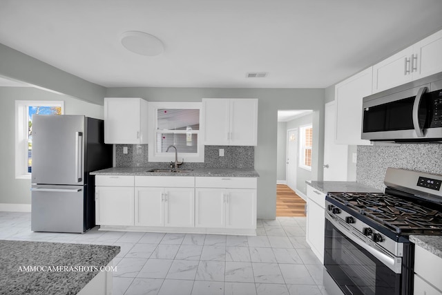 kitchen with light stone counters, a sink, white cabinetry, marble finish floor, and appliances with stainless steel finishes