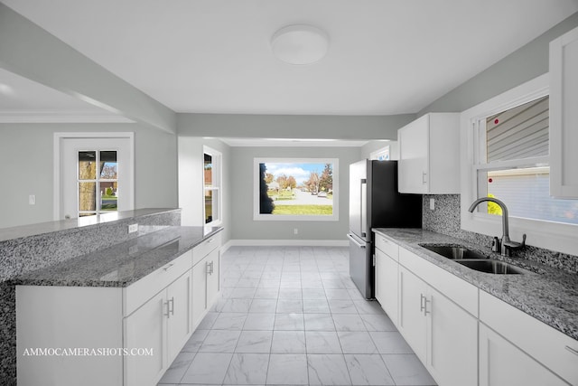 kitchen with stone counters, marble finish floor, white cabinetry, and a sink