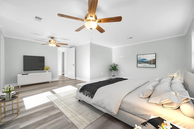 bedroom featuring light wood-style floors, visible vents, and crown molding