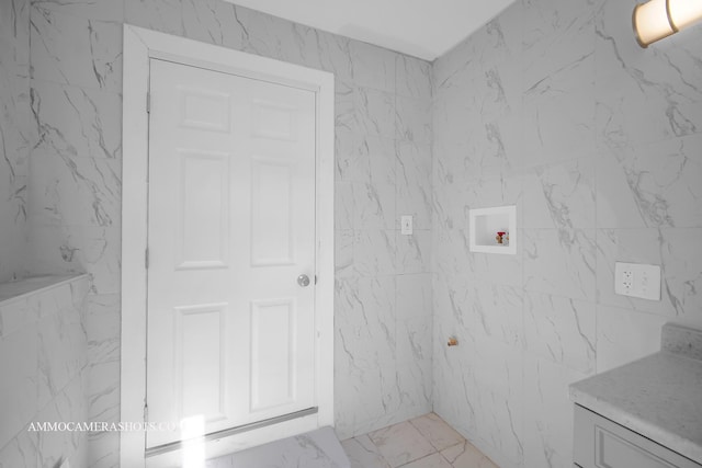 bathroom featuring marble finish floor and stone wall