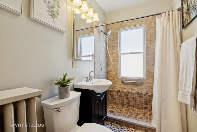 bathroom featuring toilet, a tile shower, a wealth of natural light, and vanity