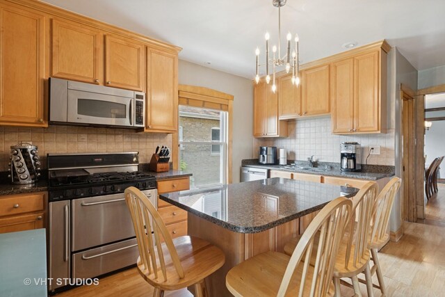 kitchen with a chandelier, backsplash, appliances with stainless steel finishes, and light wood finished floors