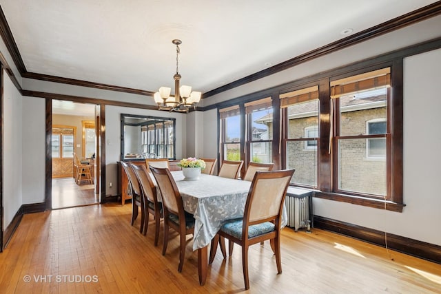 dining room with light wood-style floors, radiator, baseboards, a notable chandelier, and crown molding