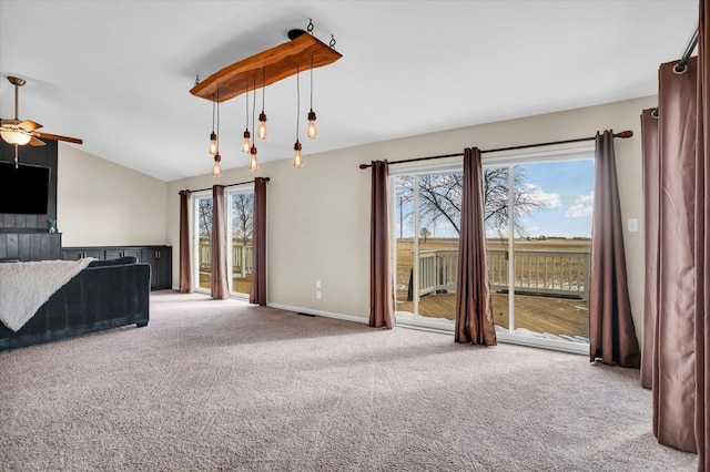 unfurnished living room featuring ceiling fan, light colored carpet, visible vents, baseboards, and vaulted ceiling