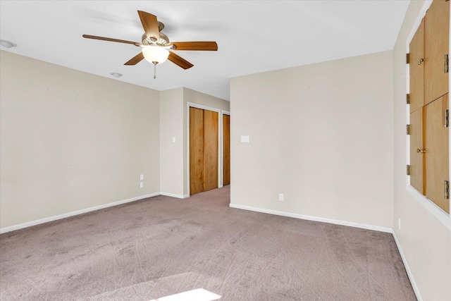 carpeted spare room featuring ceiling fan and baseboards