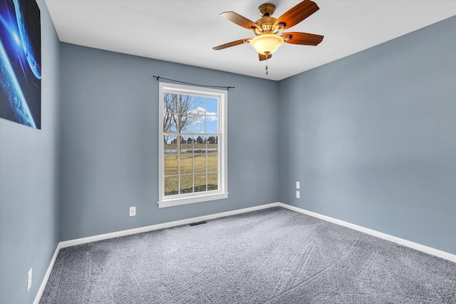 carpeted spare room featuring visible vents, ceiling fan, and baseboards